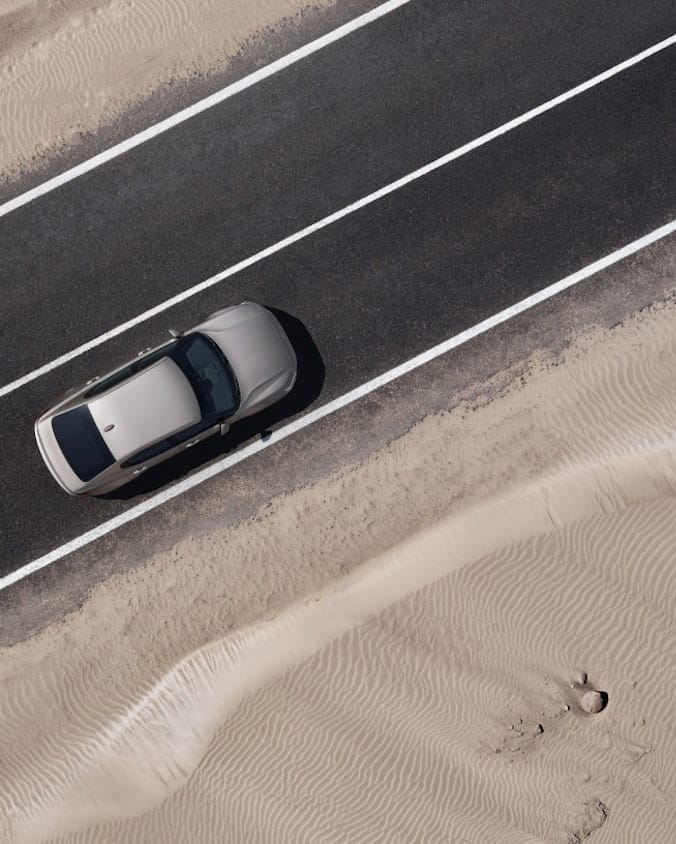 A beige Polestar 2 driving on motorway in the desert 