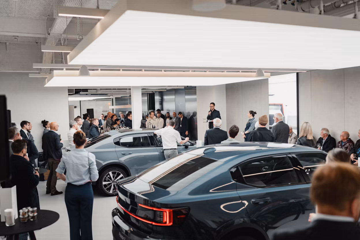 Event attendees gathered indoors near two Polestar cars with a speaker addressing the audience.