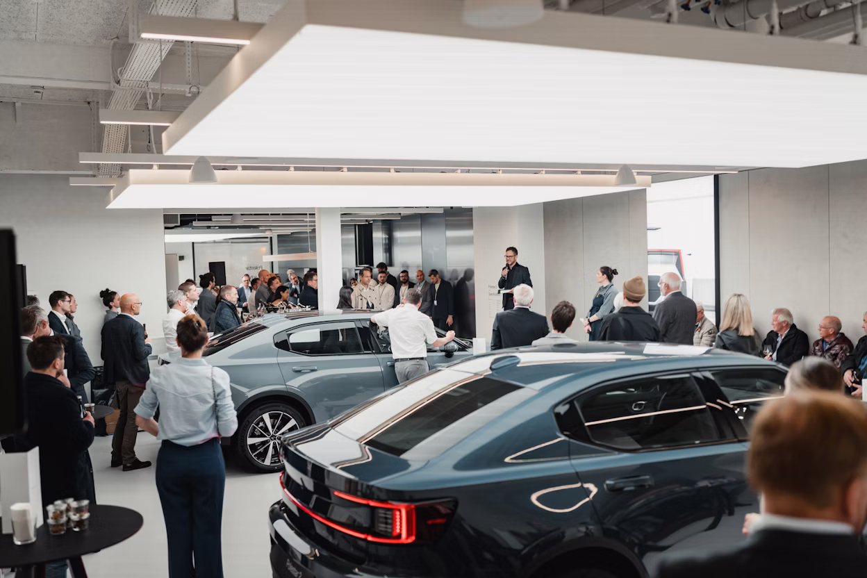 Event attendees gathered indoors near two Polestar cars with a speaker addressing the audience.