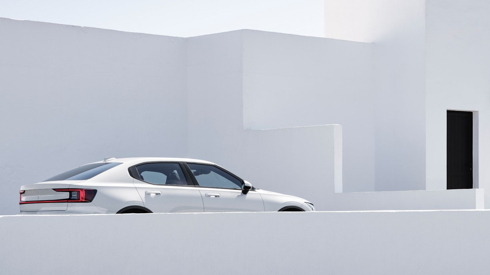 Upper part showing of a white Polestar 2 against white cement walls
