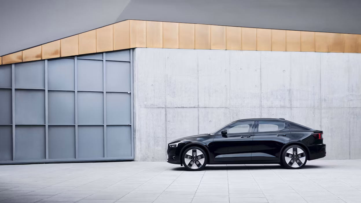 Image of a black Polestar 2 in front of a grey building.