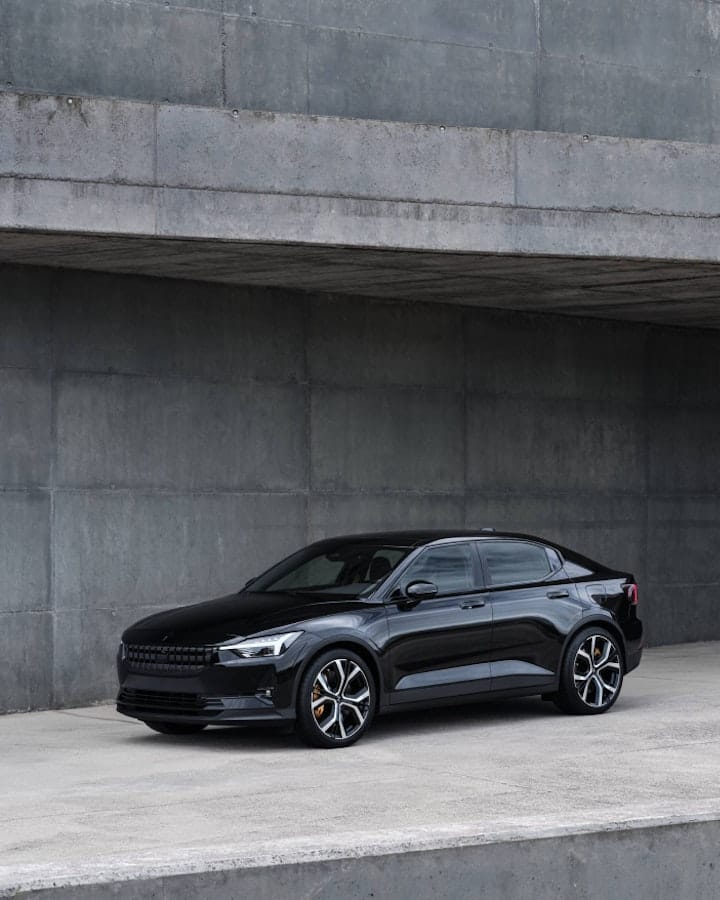 Black Polestar 2 parked against a cement-like building