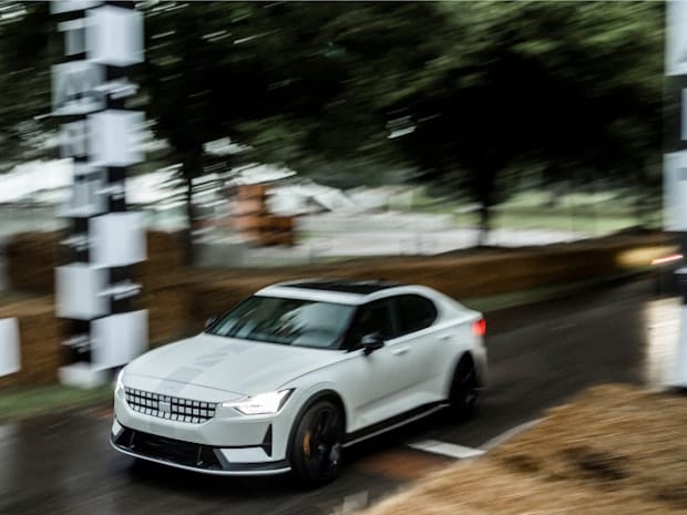 Front and side view of Polestar 2 BST edition 270, race stripe adorned racing off pole position on a racing track