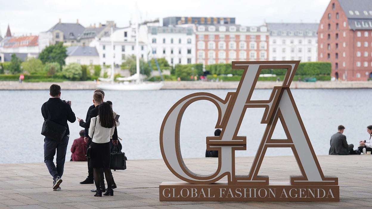 Large Global Fashion Agenda sign with people walking next to it.