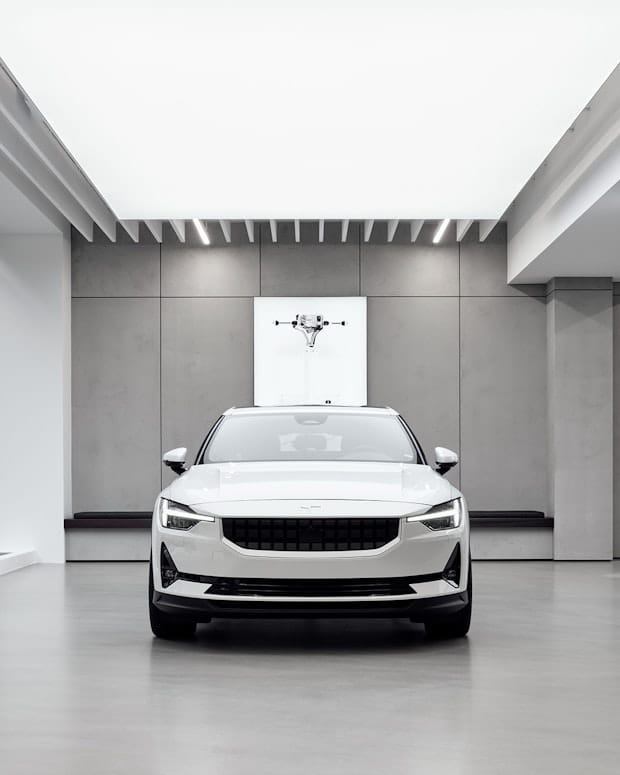 A white Polestar 2 parked inside a Polestar space with grey walls
