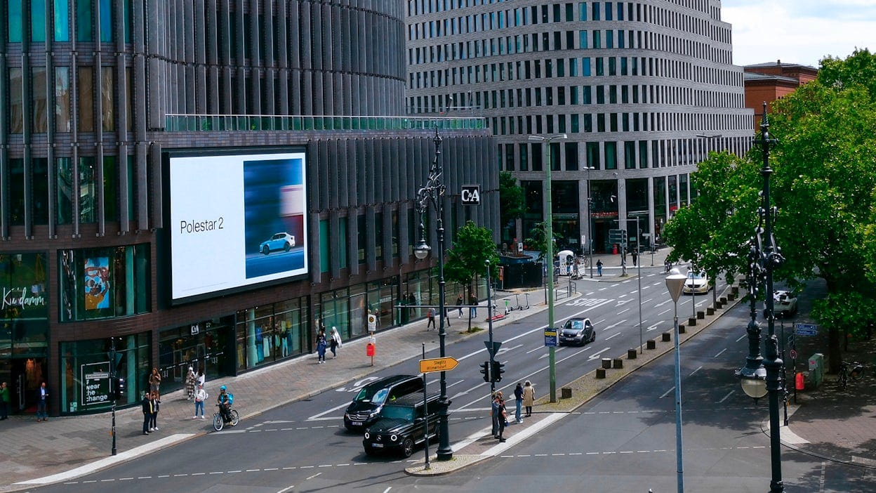 Polestar 2 digital billboard on a city building with cars driving next to it.