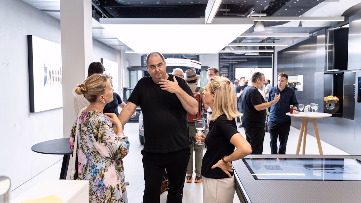 People interacting in a modern showroom with a Polestar car in the background.