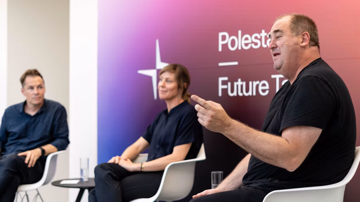 Panel discussion with three people seated on white chairs, Polestar Future Tech branding visible on gradient background.