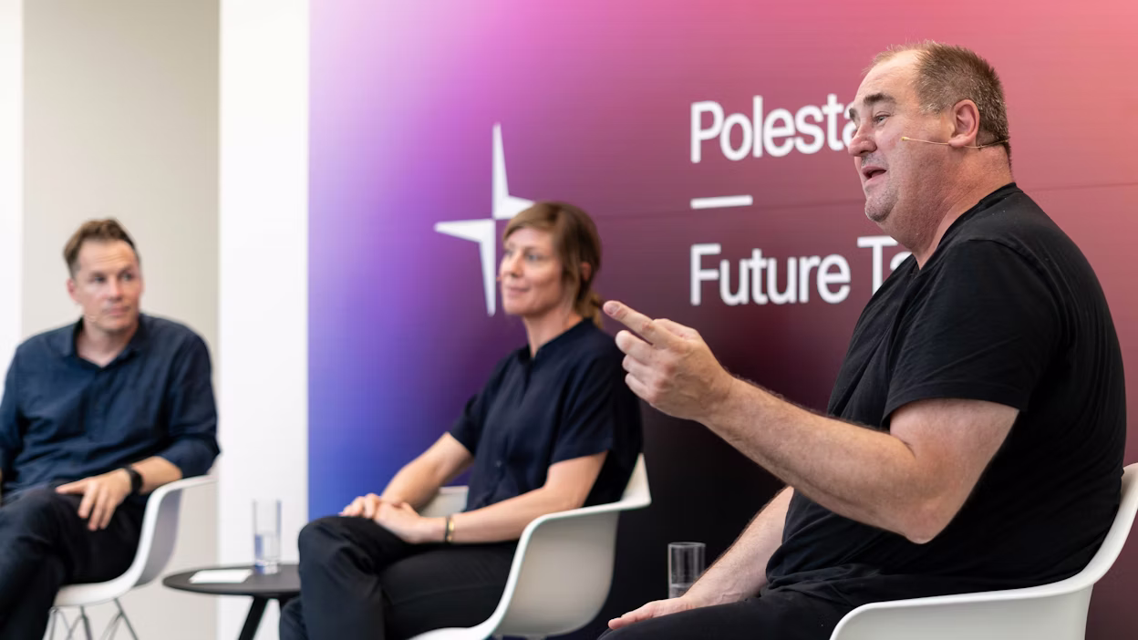 Panel discussion with three people seated on white chairs, Polestar Future Tech branding visible on gradient background.