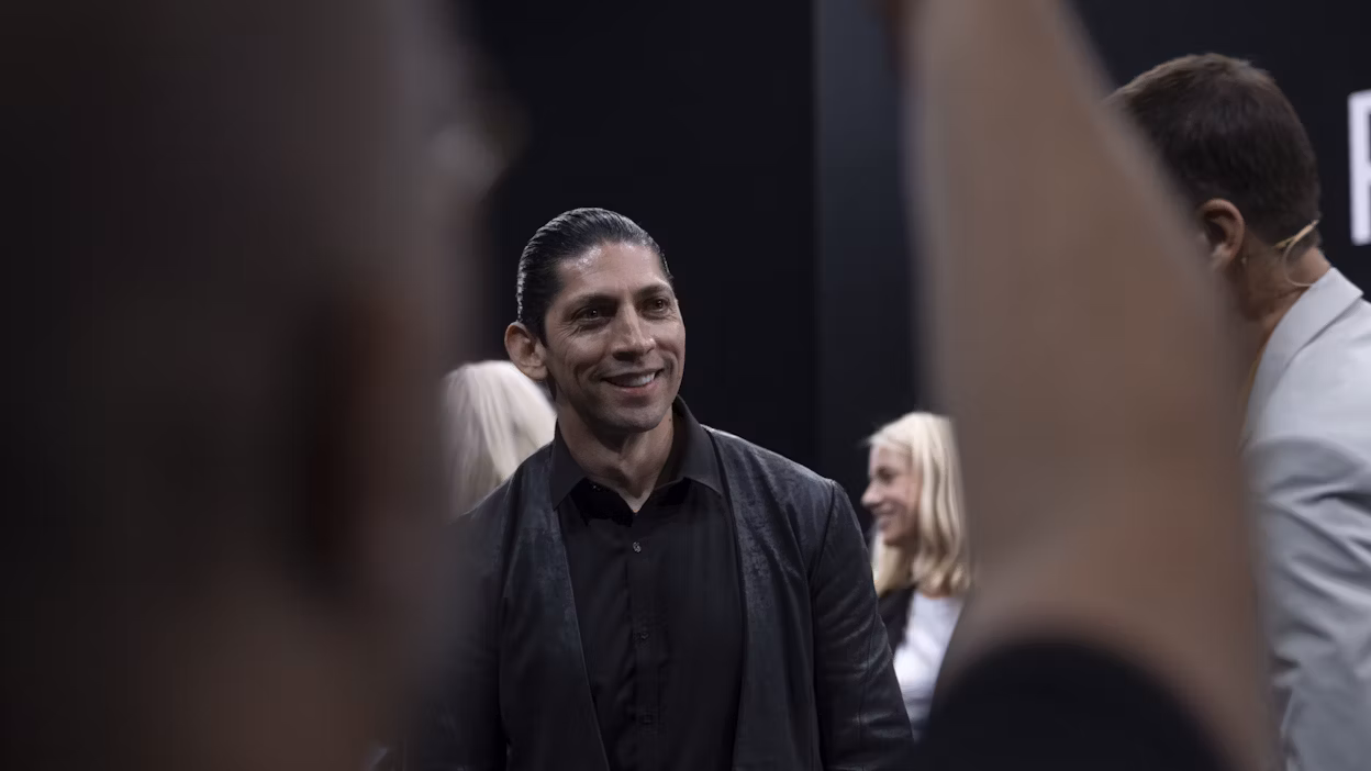 A man smiling in a crowd.