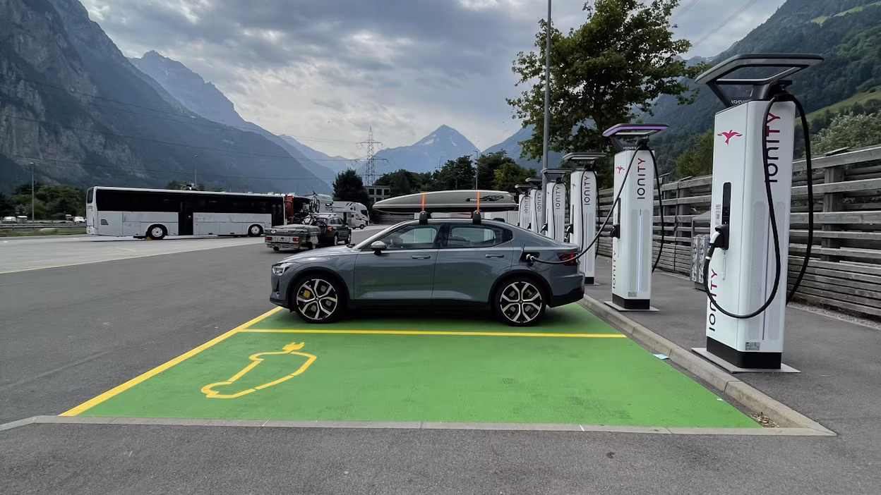 Polestar car charging at Ionity station in parking lot with mountains in background.