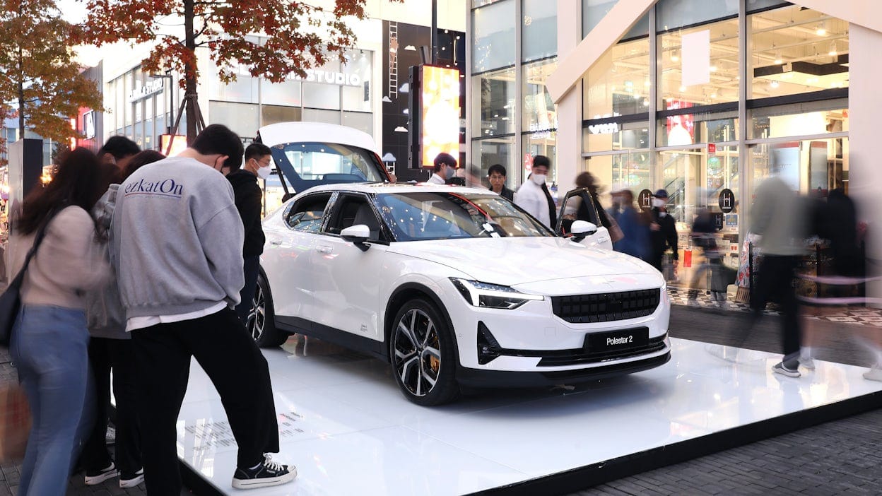 White Polestar 2 on a stand, with people surrounding it.