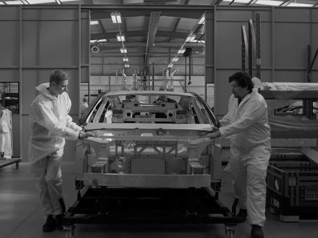 Two men on the assembly line with the body work of Polestar Precept.
