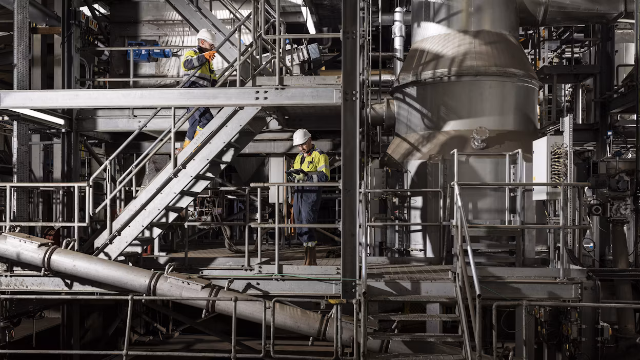 Two production workers next to the machines inside a industrial space.