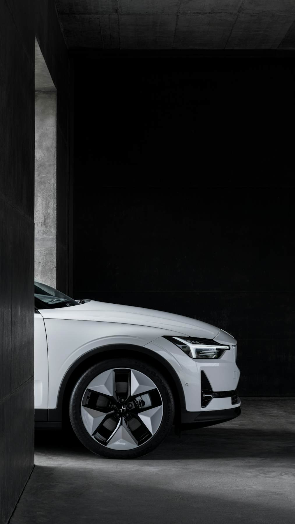 Side view of the front of a white Polestar 2 in dark background