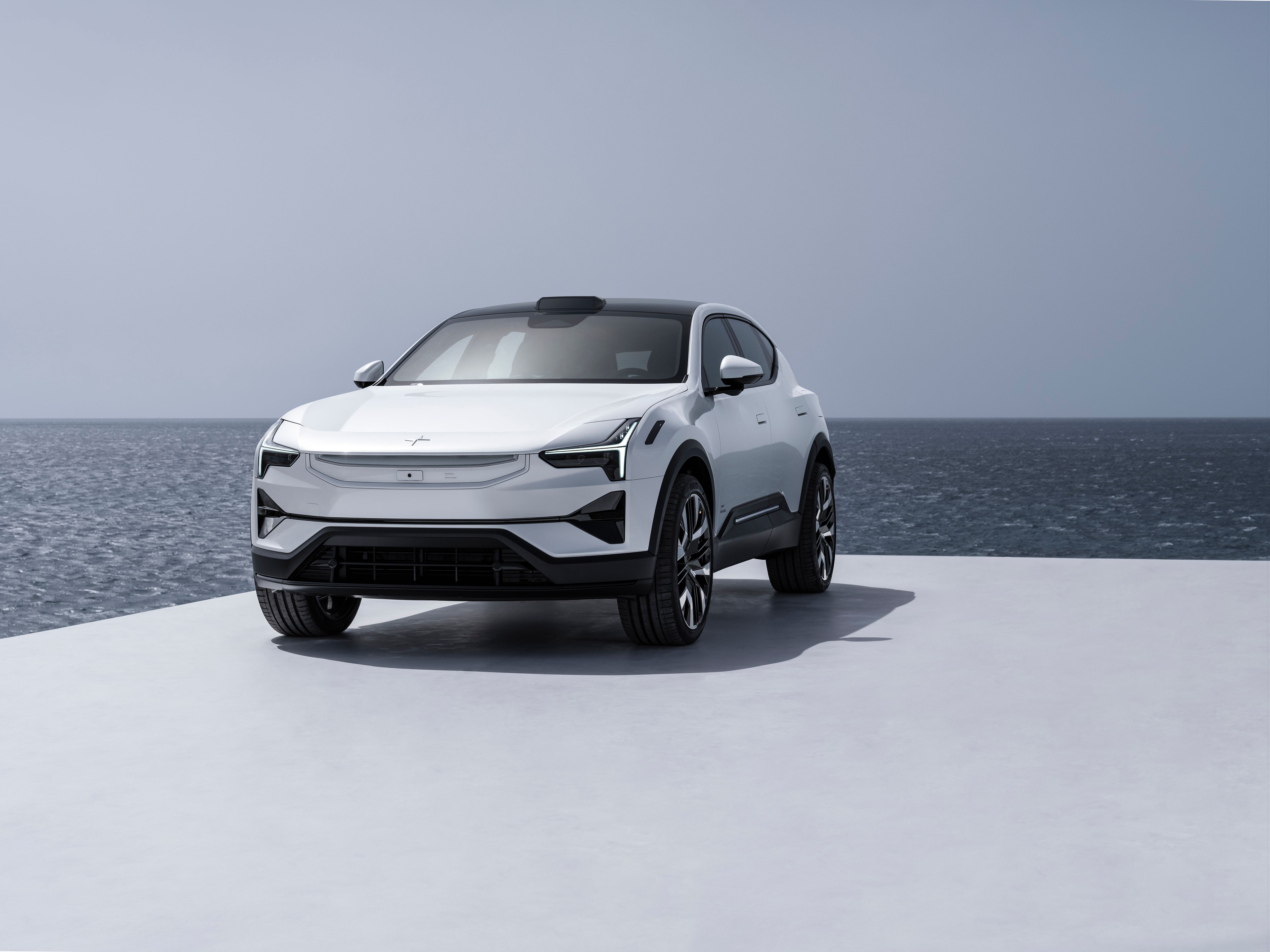 White Polestar 3 seen from the front. Standing in a white flat surface infront of the ocean.