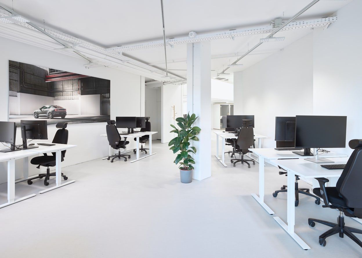 White office with black screens and chairs. Big Polestar image on the wall