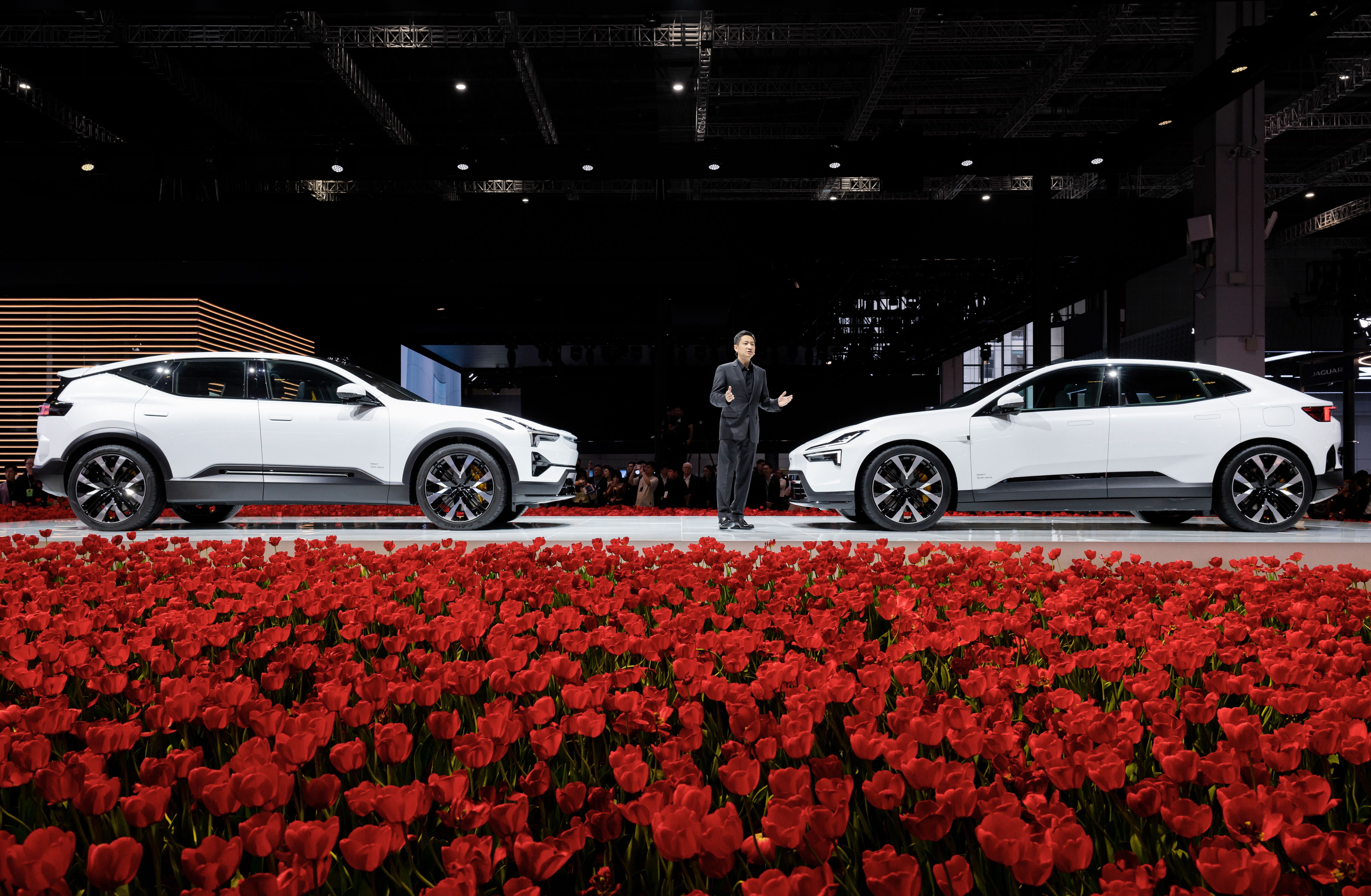 Polestar 3 and 4 facing each other on stage. A man standing in between the cars presenting