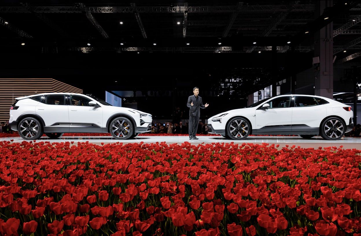 Polestar 3 and 4 facing each other on stage. A man standing in between the cars presenting