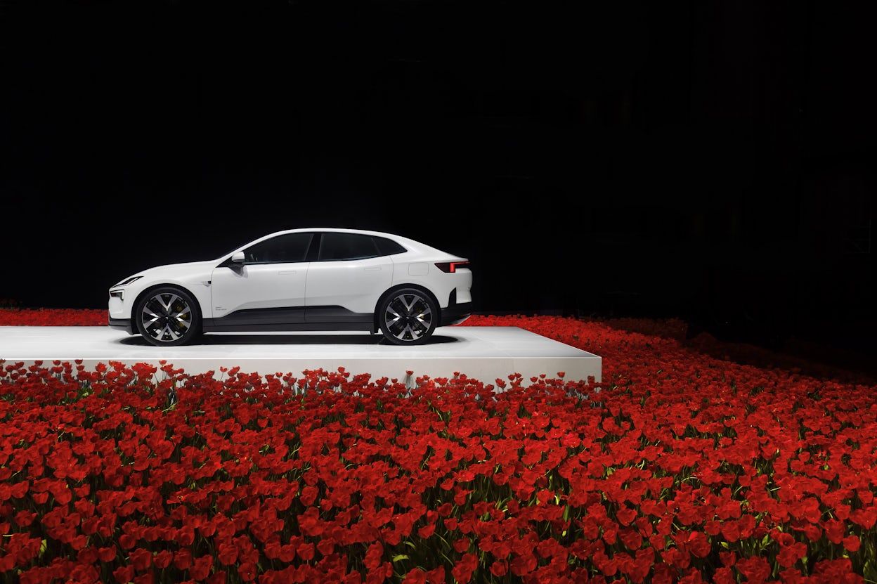Polestar 4 seen from the side on stage among red tulips
