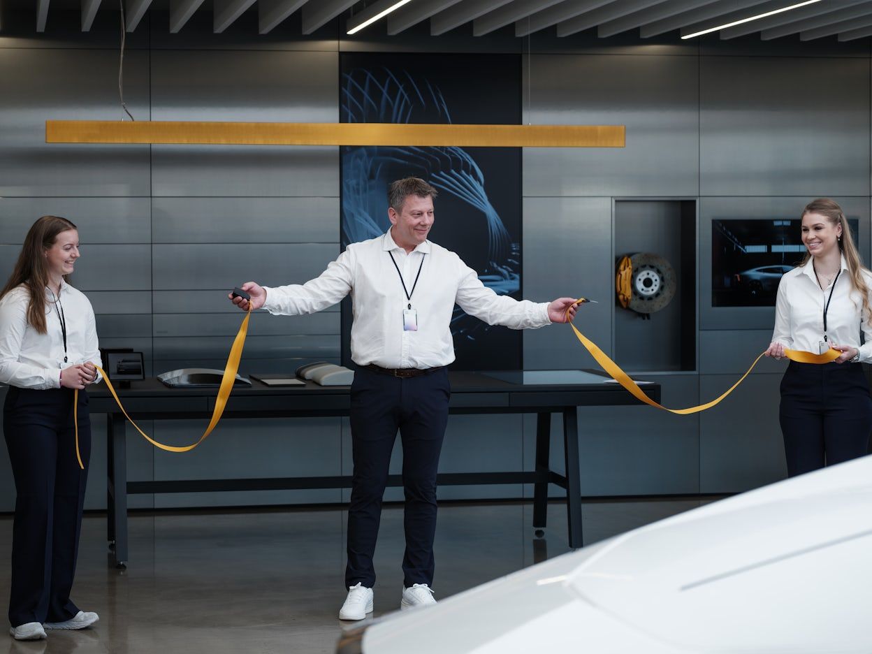 Three people cut a ribbon in connection with an inauguration of a new Polestar space