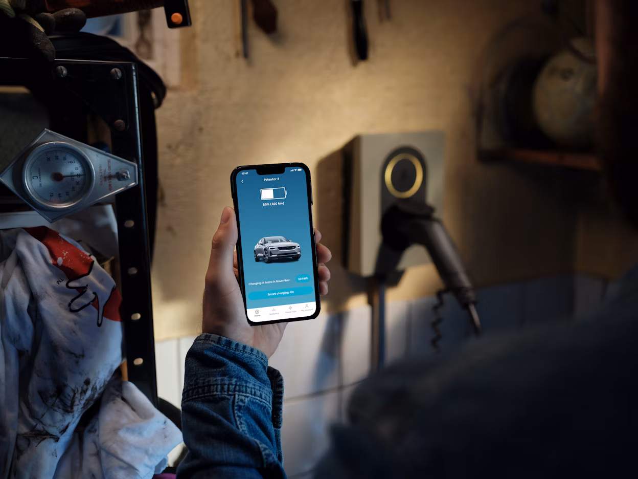 A person holding a phone showing the status of charging inside a garage