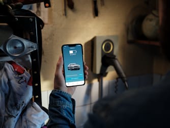 A person holding a phone showing the status of charging inside a garage