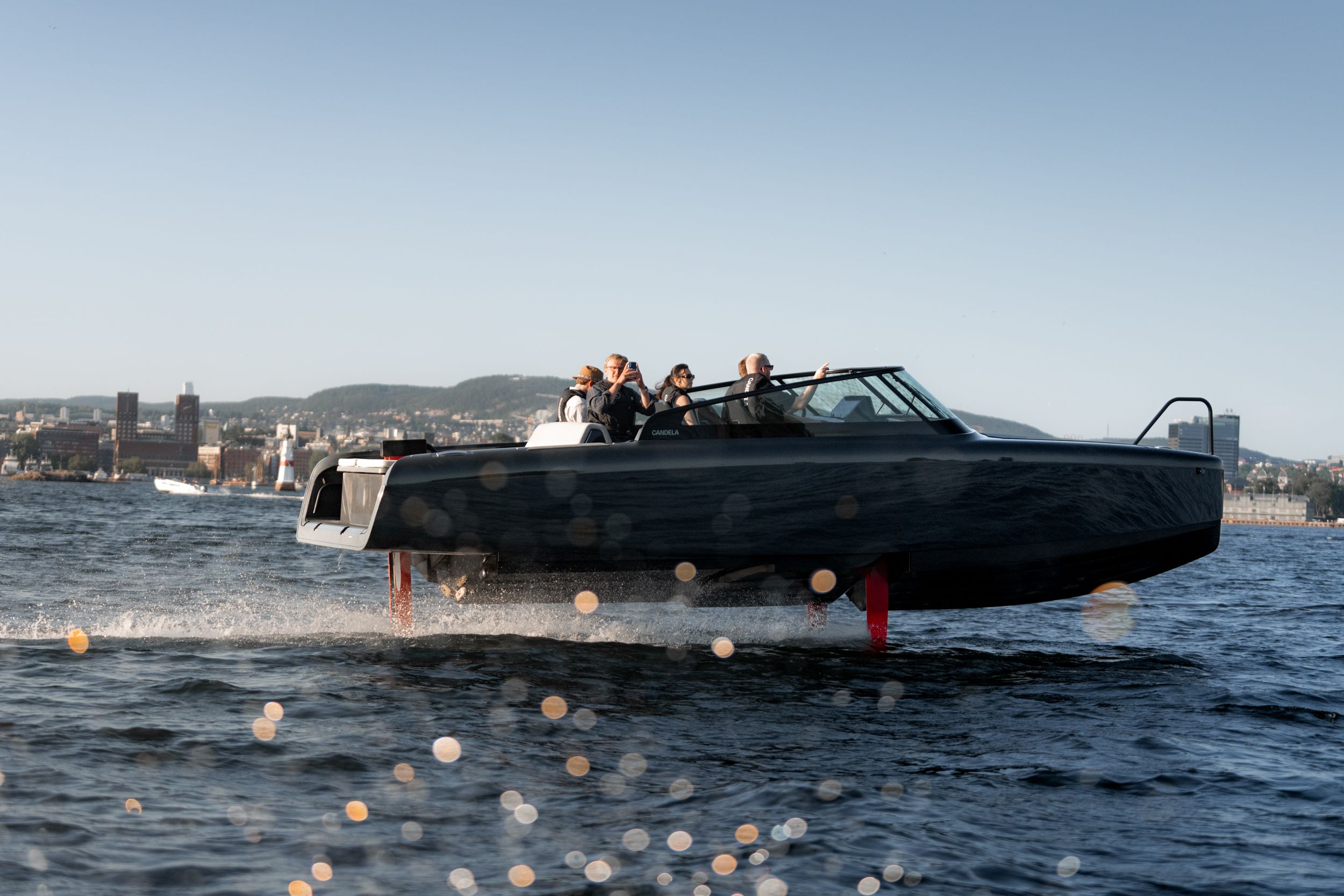 Boat with passengers gliding on water with cityscape in background.