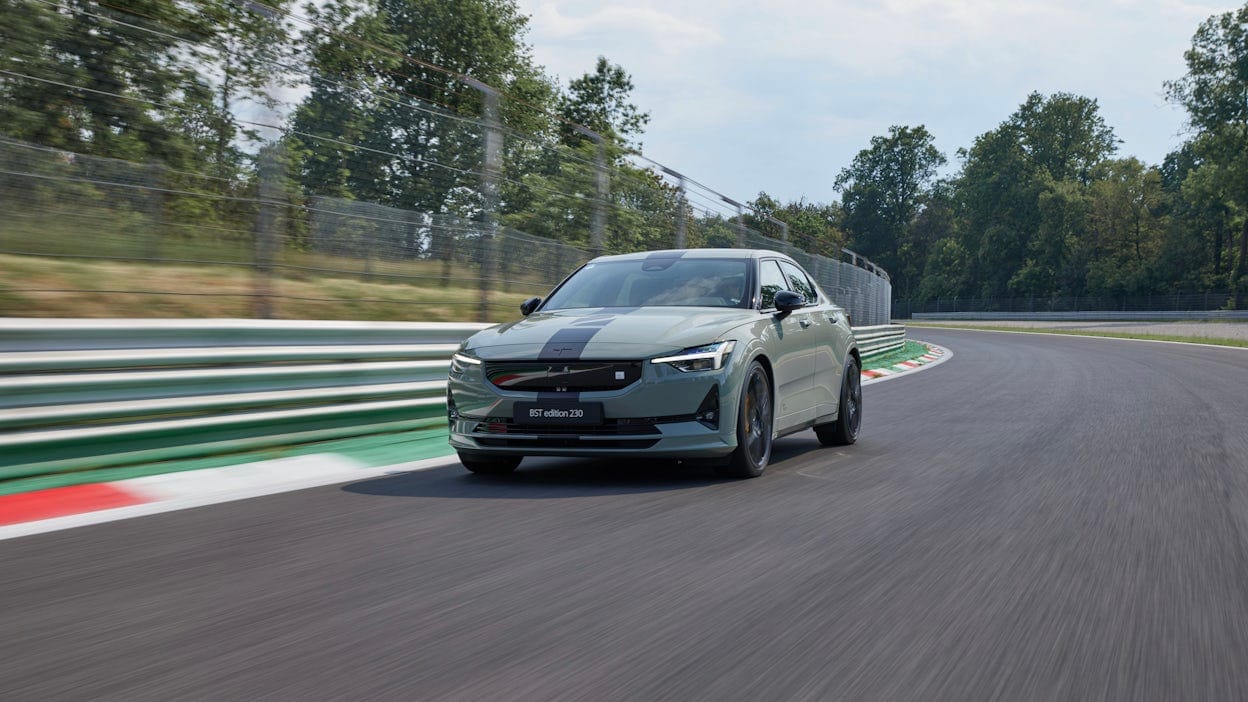 Front view of a green Polestar 2 driving on a racing track.