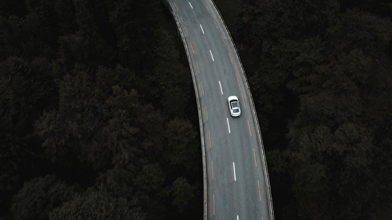 Arial view of Polestar 2 driving through middle of forest
