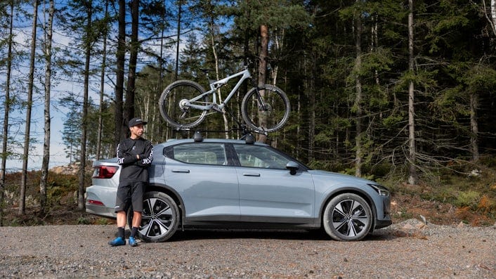 Man leaning on side of Polestar 2 with bike on roof