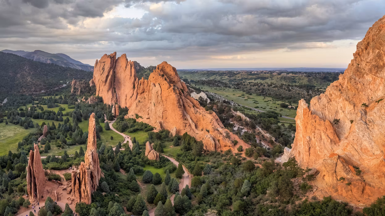 Majestic rock formations against a backdrop of a cloudy sky and lush greenery.