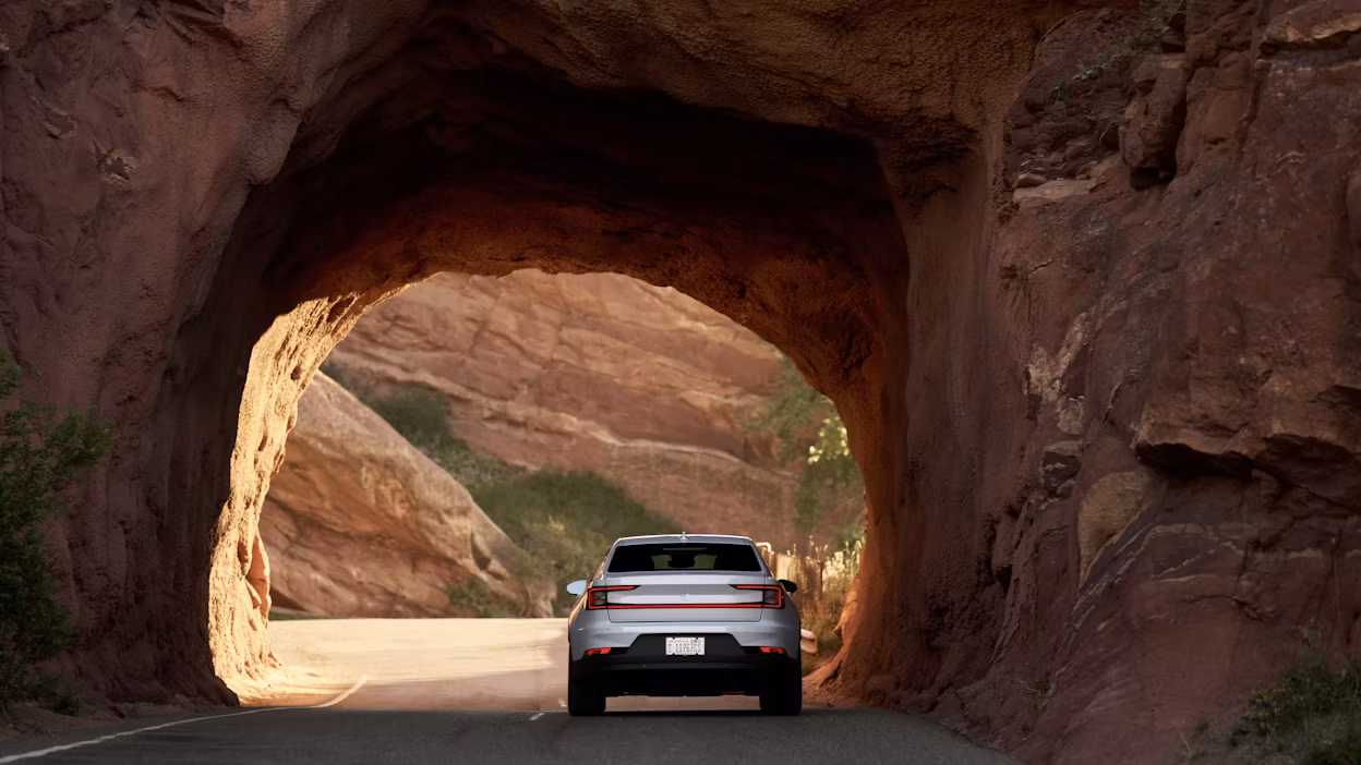 Back view of a white Polestar 2 driving through a mountain tunnel.