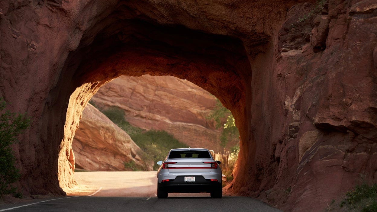 Back view of a white Polestar 2 driving through a mountain tunnel.
