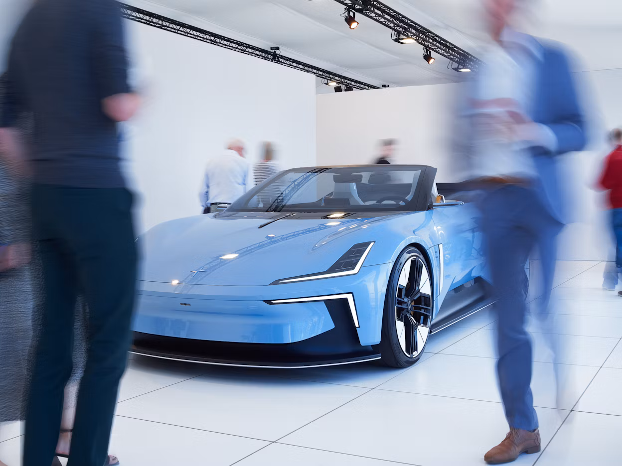 Polestar car displayed in a showroom with people walking around.
