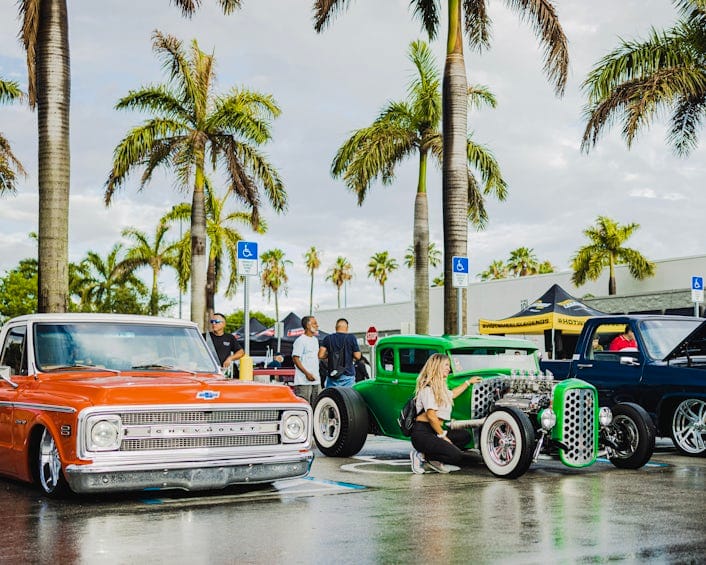 Two custom cars parked under palm trees