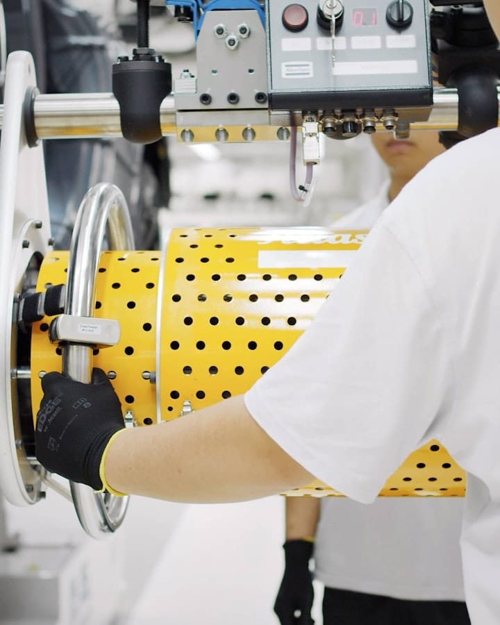 Two persons working on equipment in the Polestar factory.