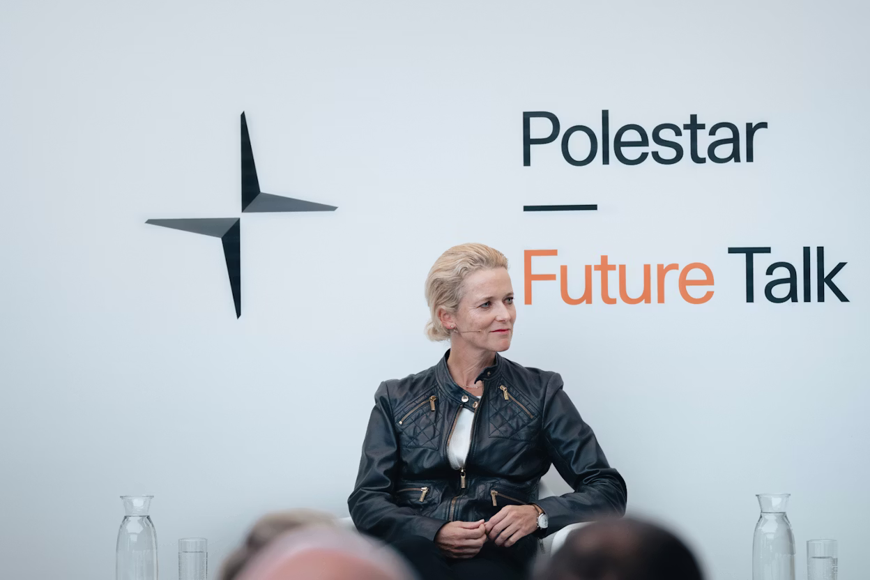 Polestar logo and Future Talk text on a white wall with glass water bottles on a table.