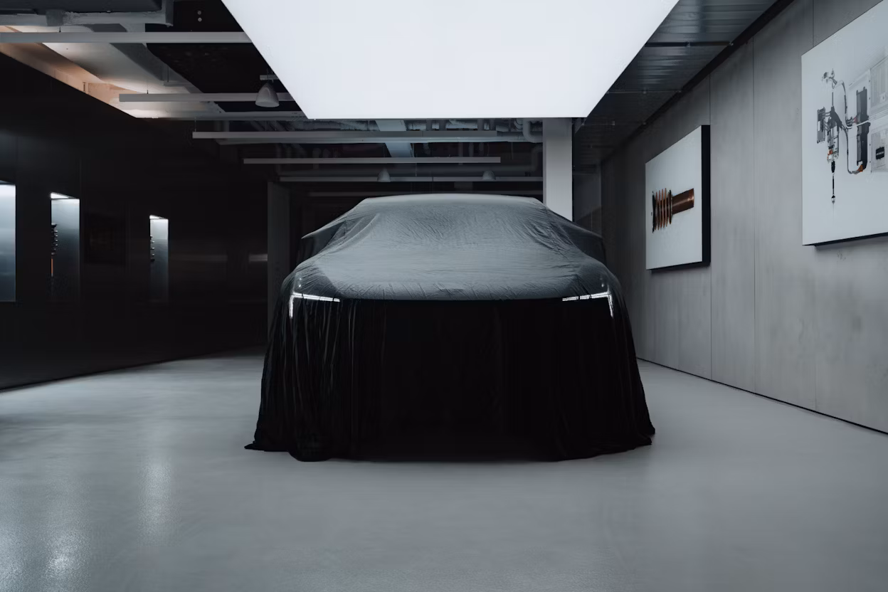 Polestar car covered with black fabric in a modern showroom with wall-mounted artwork and ceiling lights.