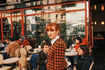Woman infront of café looking into camera.