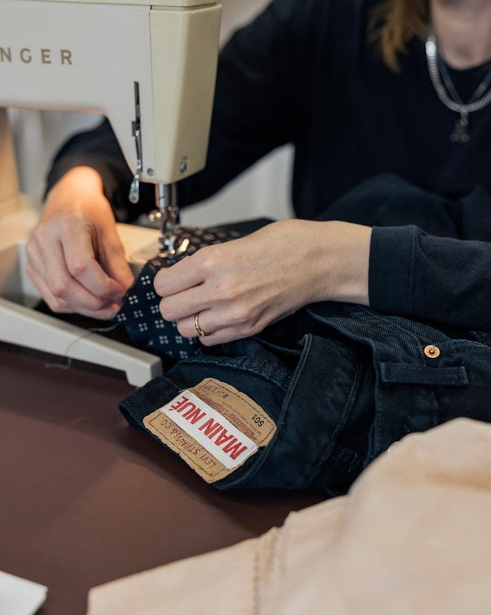 close up of Maja using a sewing machine on a pair of jeans