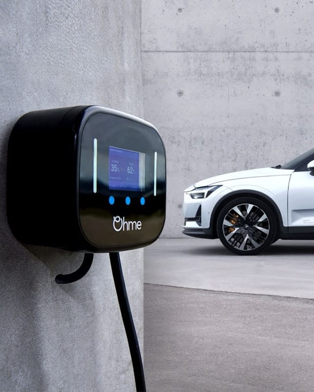 A white Polestar 2 parked to behind and to the right of an Ohme home EV charger, against a grey background.