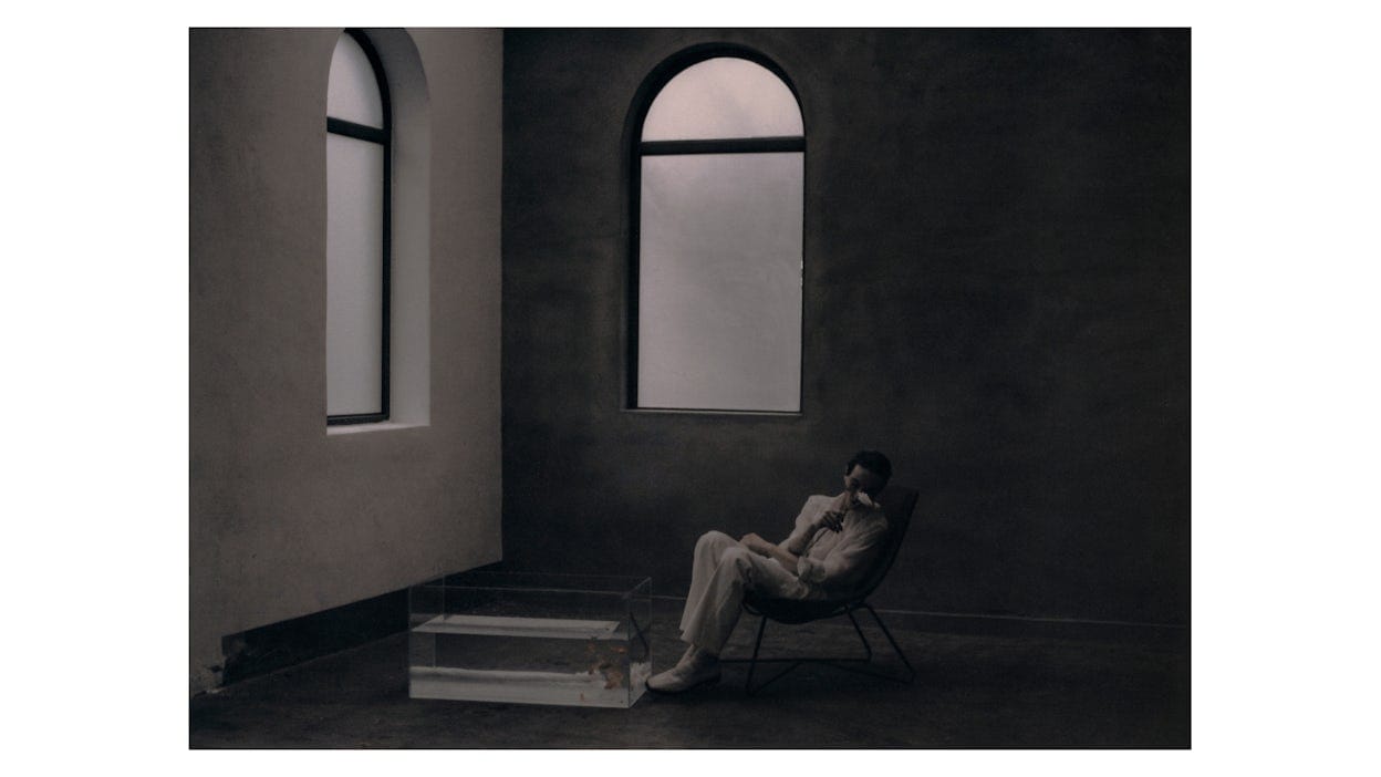 Rala Choi's work "Men & Pleasure". Pictured: A man sitting in a room with a rose covering his face.