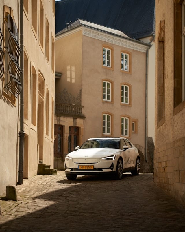 Polestar 2 in white driving down a narrow street in a french town