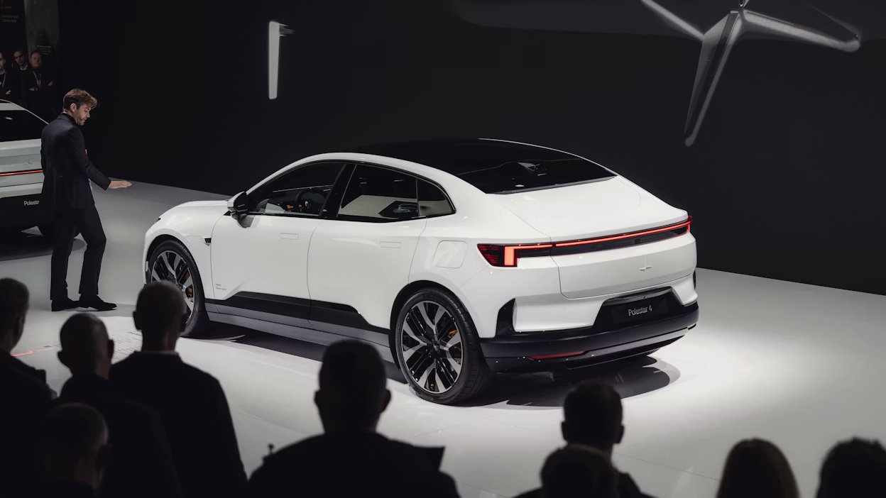 White Polestar car displayed on stage with audience in foreground and dark background.