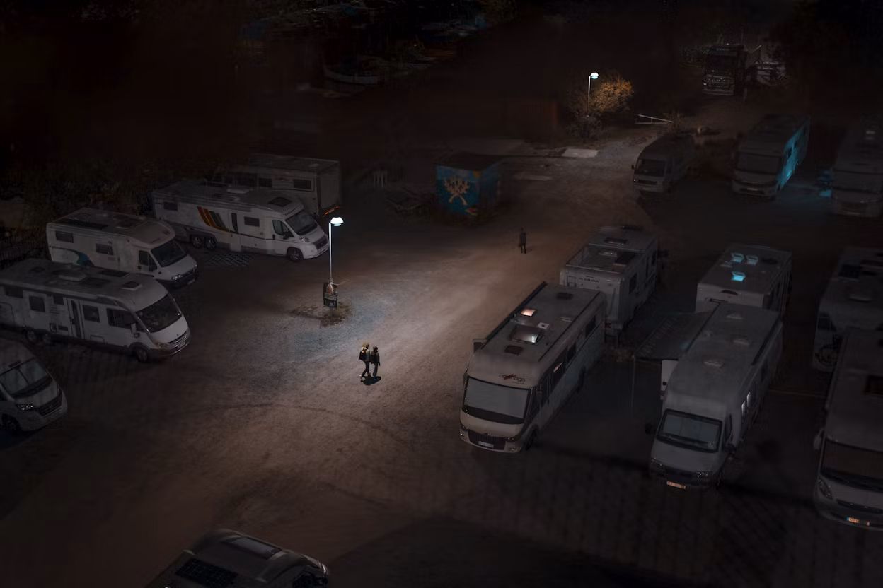 Three people walking through a dark caravan parking lot.
