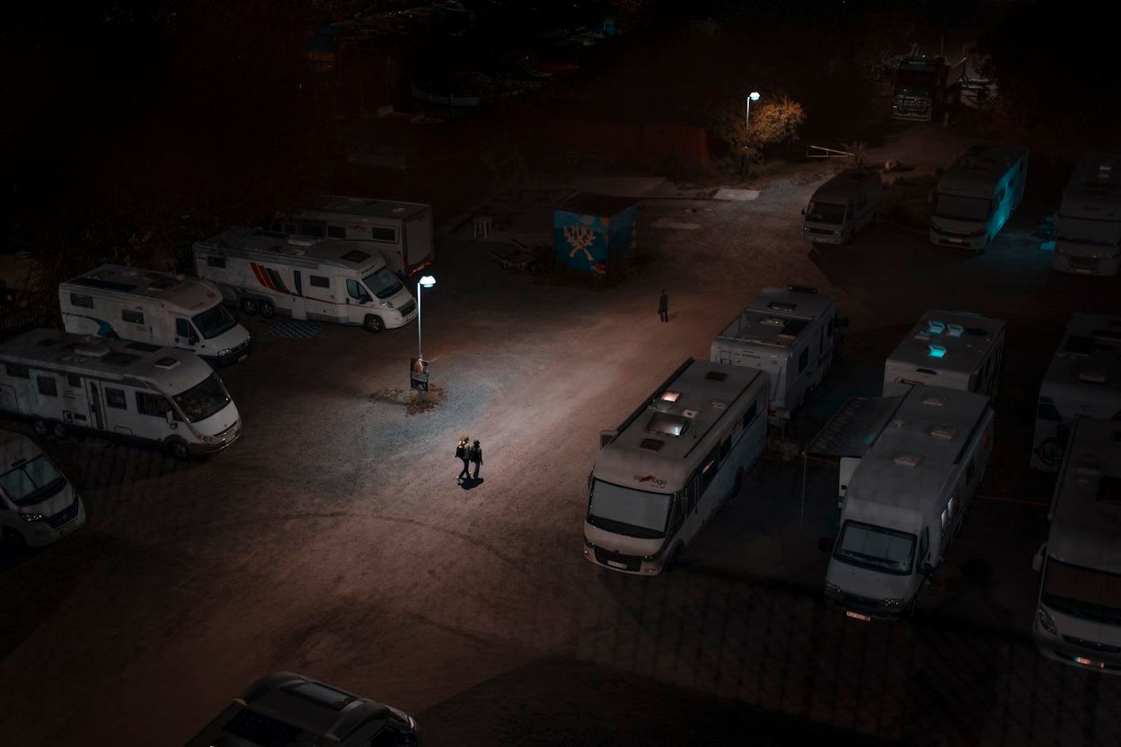 Three people walking through a dark caravan parking lot.