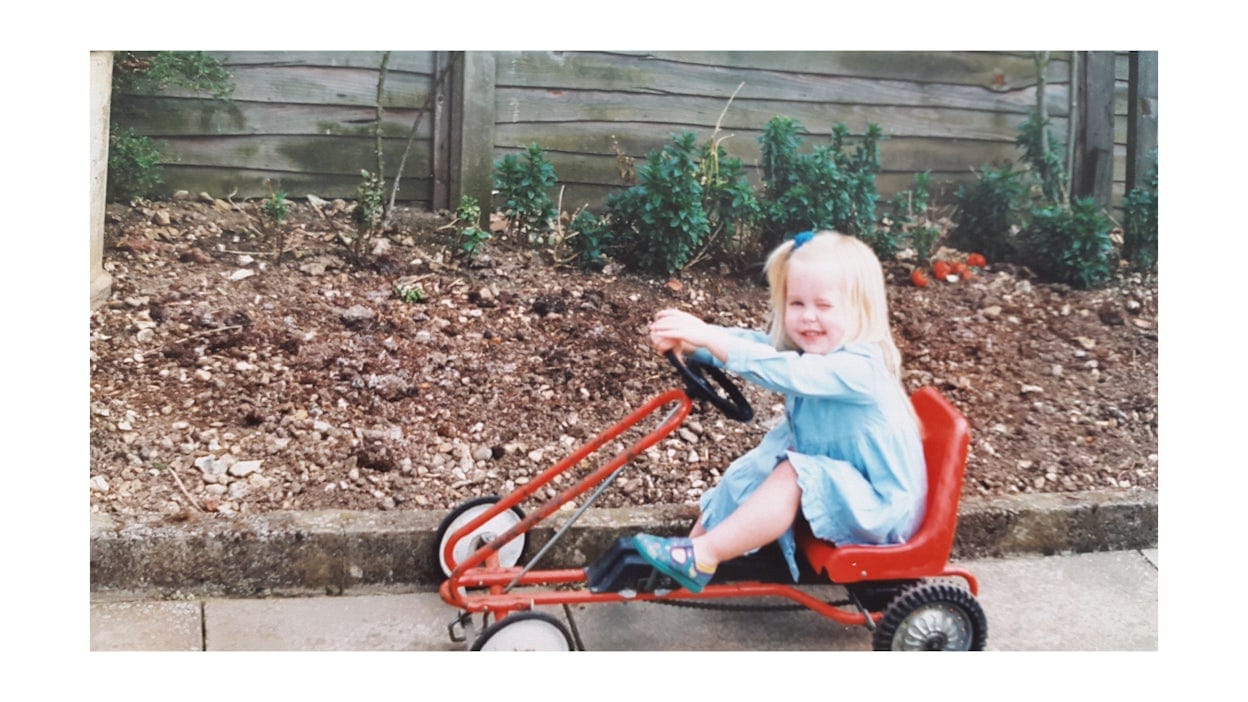 An old photography of Bethany as a child, riding a toy-car.