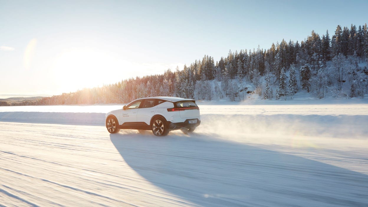 Polestar 3 in Snow color driving on a snowy road with the sun shining