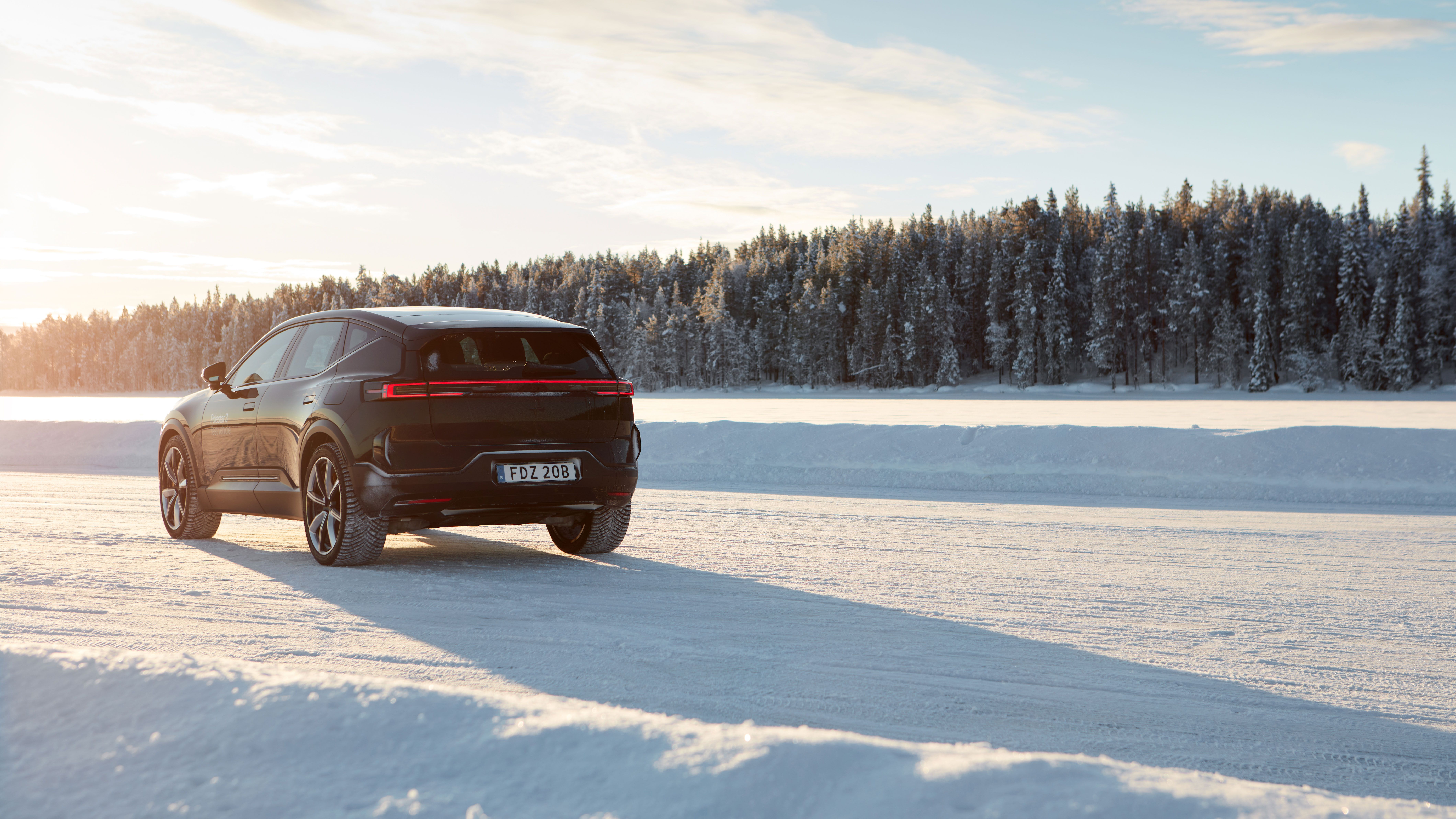 Polestar 3 in Space color driving on a snowy road with the sun shining